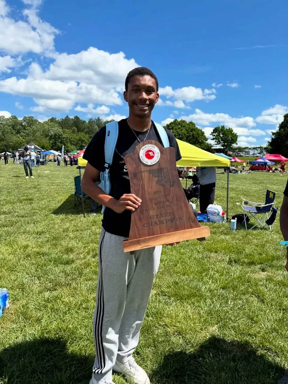 Christian Wilbon posing with track award plaque outdoor field segment
